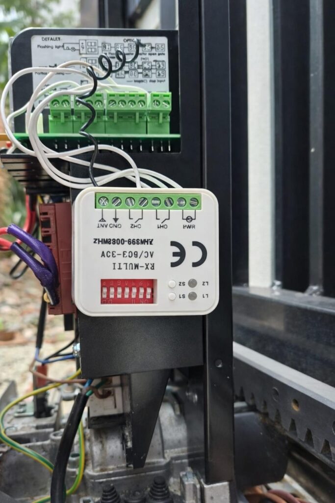 Aftermarket receiver wired into sliding gate motor control board for remote compatibility